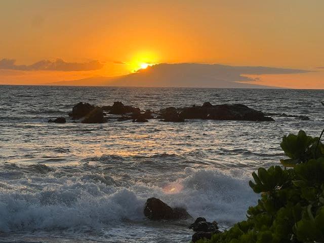 Dramatic Maui ocean sunset over rocky coastline with waves crashing