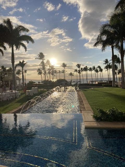 Luxury Maui resort fountain at sunset with palm trees and golden sky